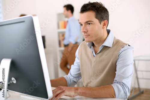 Man working in office in front of desktop computer