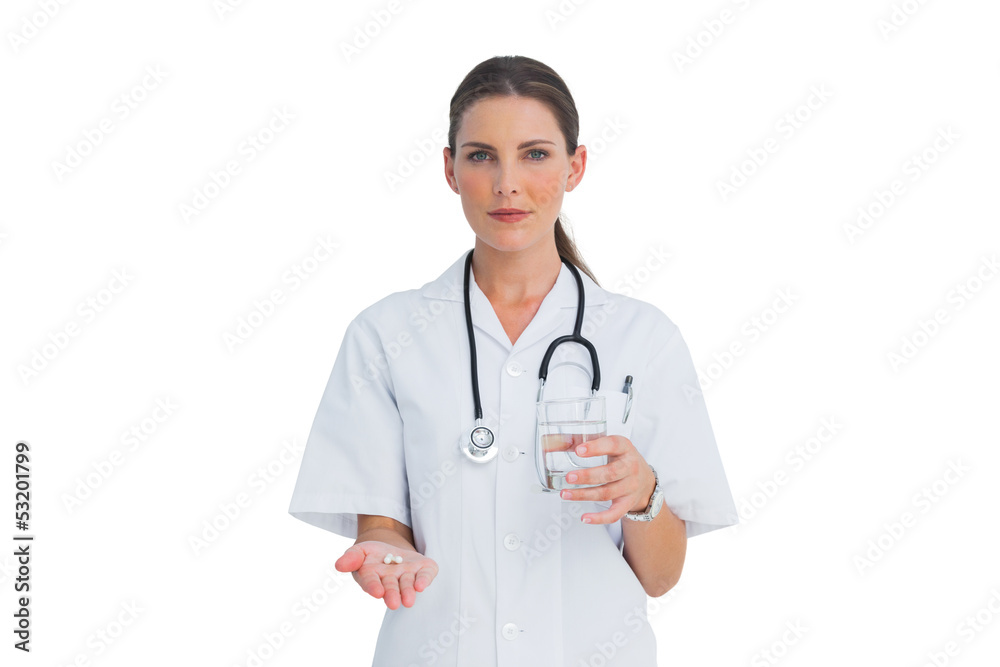 Serious nurse holding medicine and glass of water Serious nurse holding medicine and glass of water