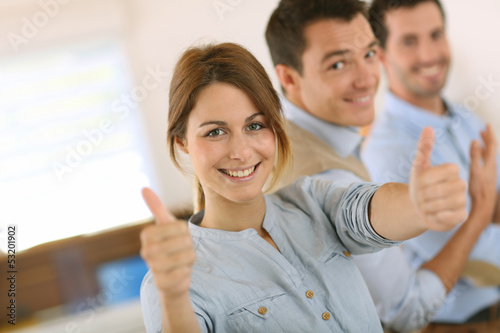Cheerful girl in office showing thumbs up