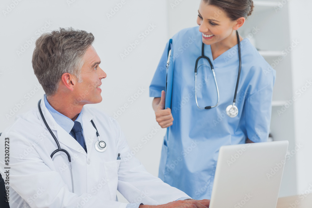 Doctor with a clipboard talking to a colleague Doctor with a clipboard talking to a colleague