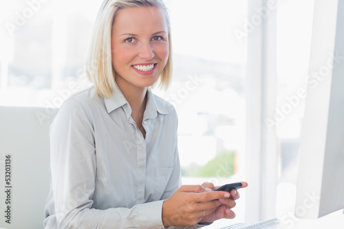 Blonde businesswoman texting and smiling at camera © WavebreakmediaMicro