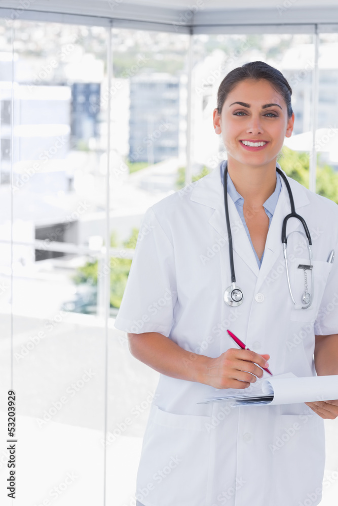 Doctor smiling at camera and holding clipboard and pen Doctor smiling at camera and holding clipboard and pen