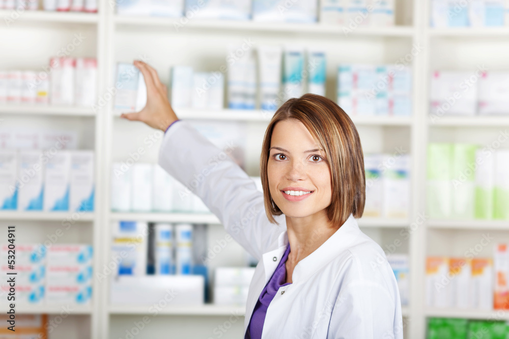 female pharmacist taking medicine from shelf