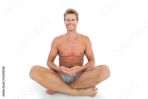 Cheerful man with eyes closed meditating on the floor