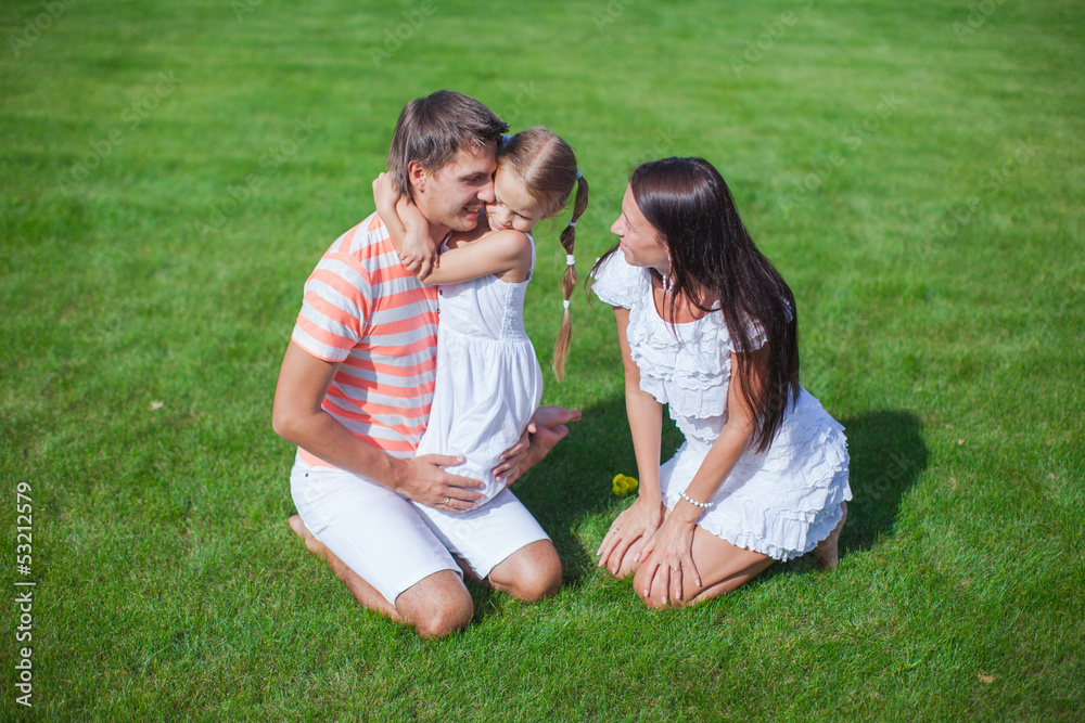 young family of three sit on the grass and have fun young family of three sit on the grass and have fun