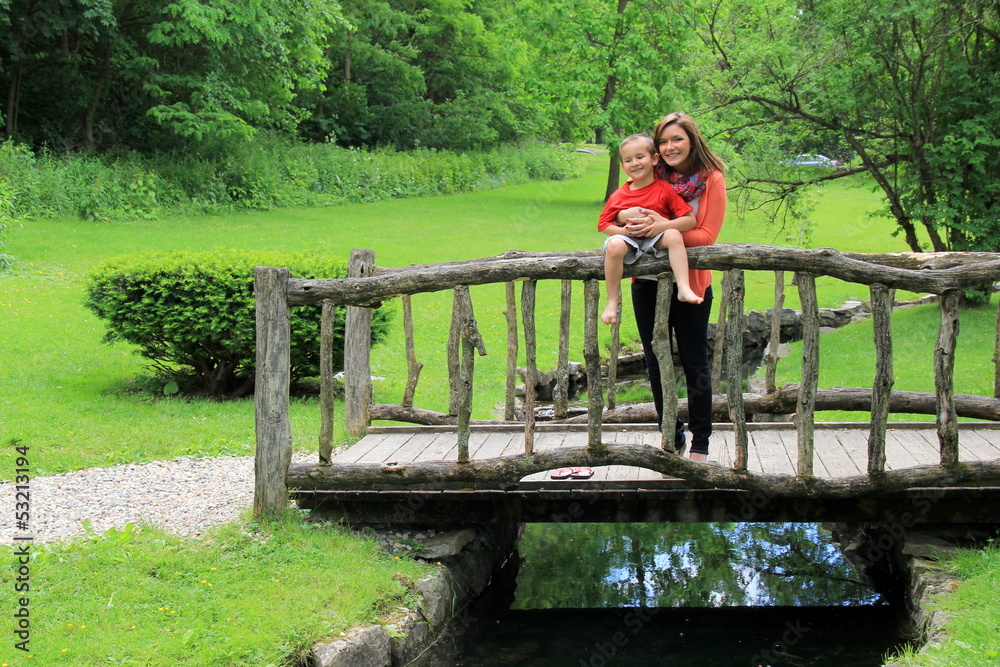 Young mother and son on old wooden bridge Young mother and son on old wooden bridge