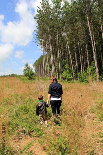 Young brunette mother and son walking in meadow