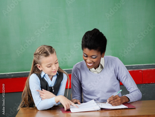Schoolgirl Asking Question To Teacher At Desk