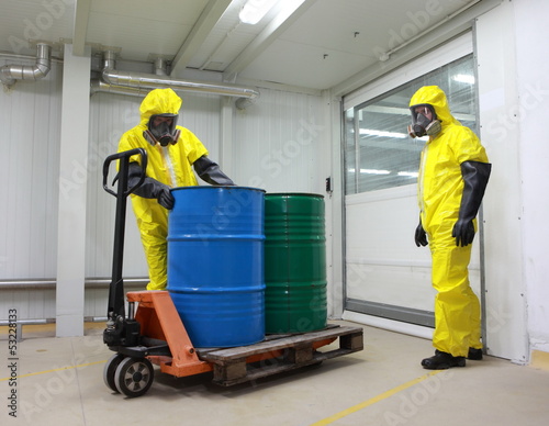 Workers in protective uniforms  wh barrels of toxic substance