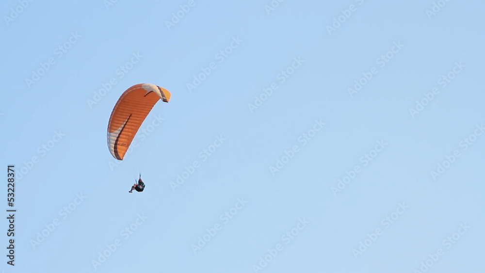 Paragliding over the mountains against clear blue sky Paragliding over the mountains against clear blue sky