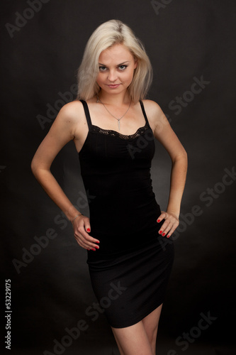 Beautiful girl in a short black dress on a black background.
