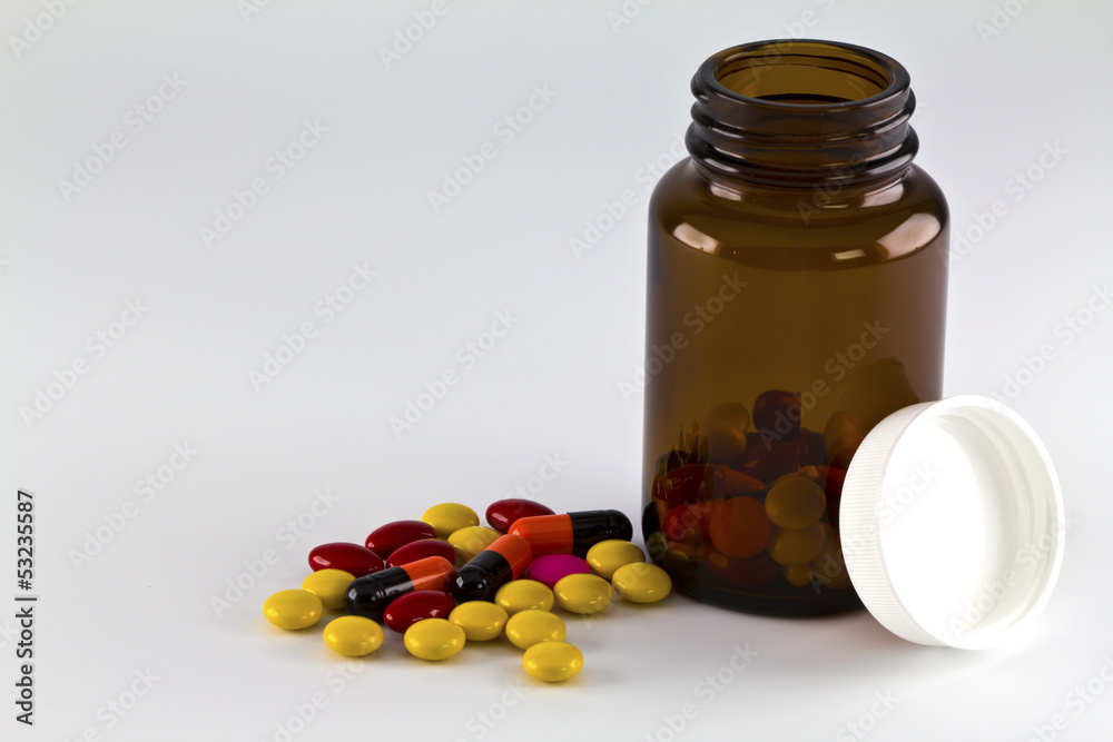 Pills, Tablets and Capsules spilled from a bottle on white backg Pills, Tablets and Capsules spilled from a bottle on white backg