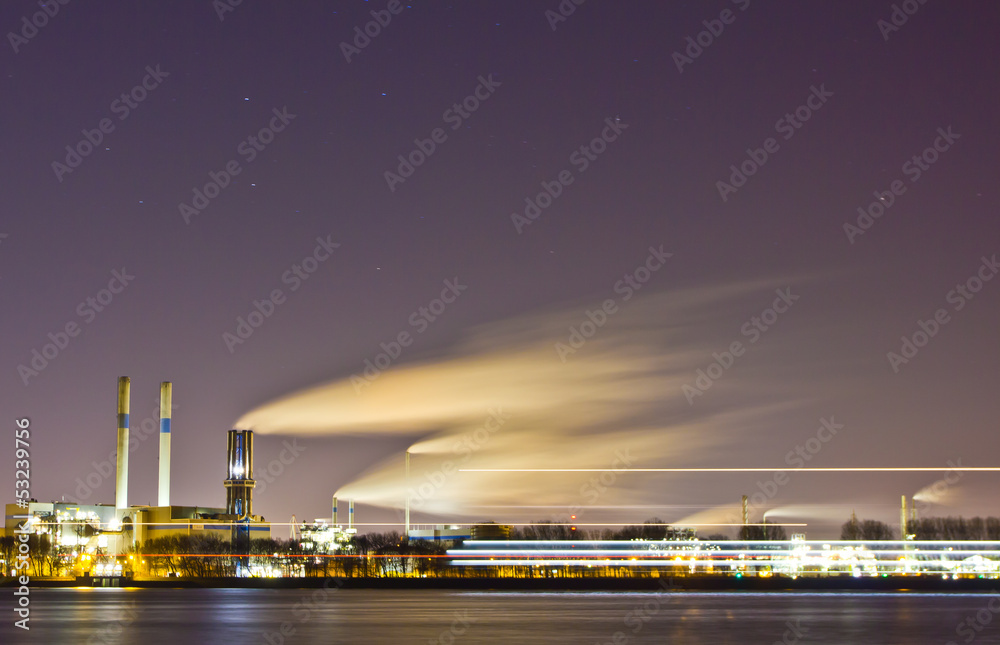 Oil refinery at night with passing boat