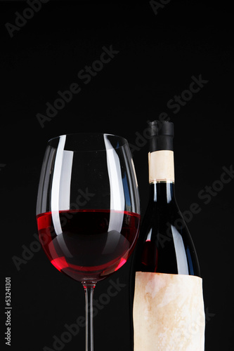 Glass of wine with bottle on bright background