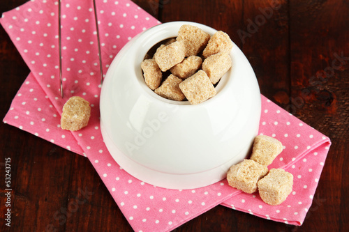 Unrefined sugar in white sugar bowl on wooden background photo