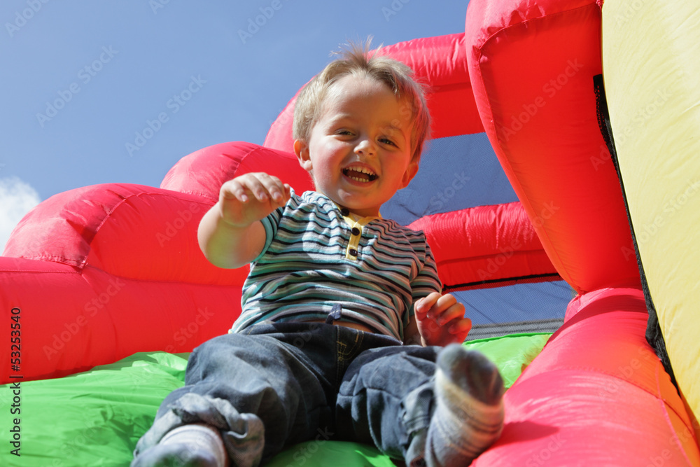 Fototapeta premium Child on inflatable bouncy castle slide