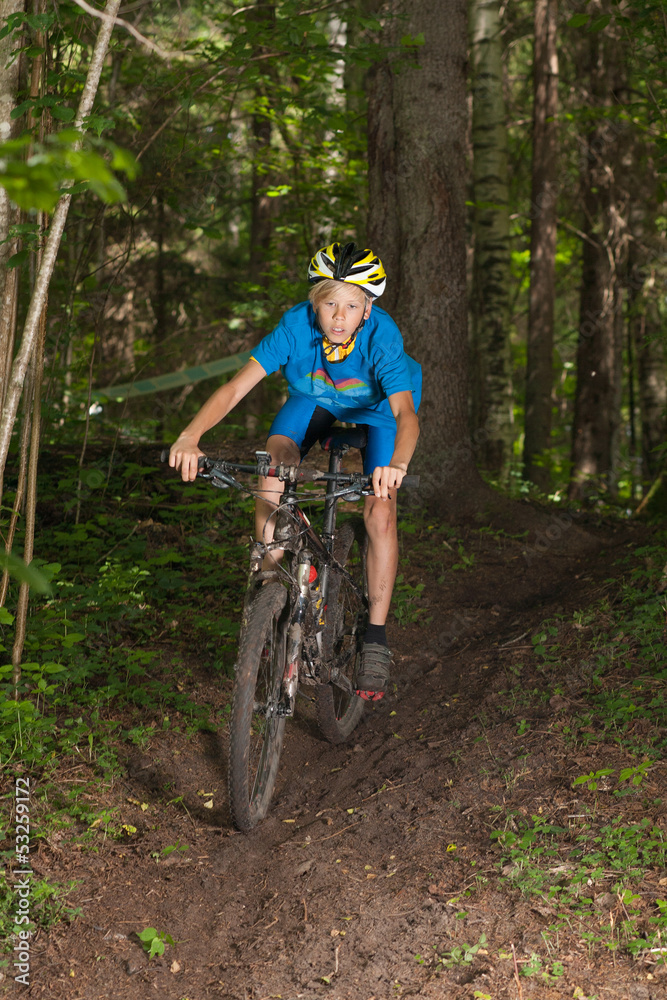 Young cyclist riding downhill in forest Young cyclist riding downhill in forest