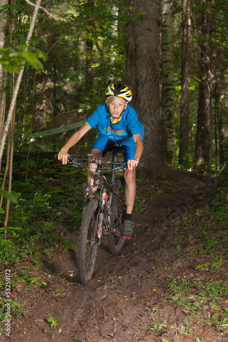 Young cyclist riding downhill in forest