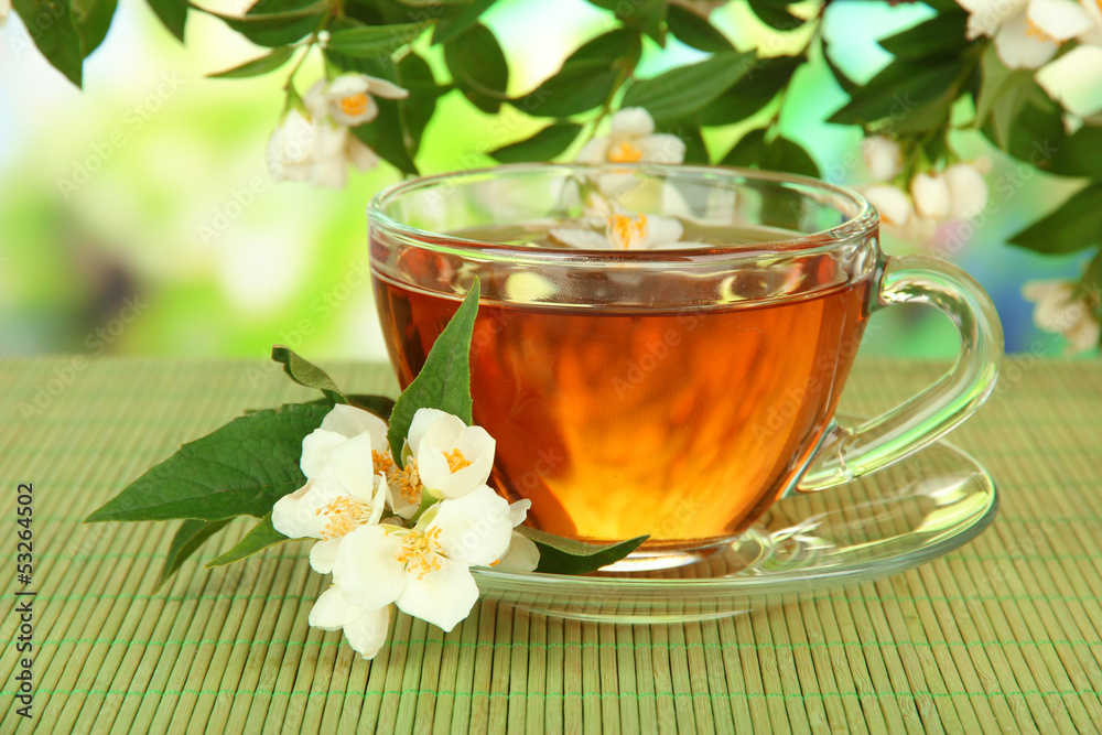 Cup of tea with jasmine, on bamboo mat, on bright background Cup of tea with jasmine, on bamboo mat, on bright background