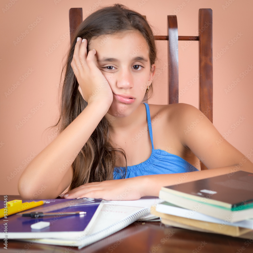 Bored and tired hispanic student with a desk full of books Bored and tired hispanic student with a desk full of books
