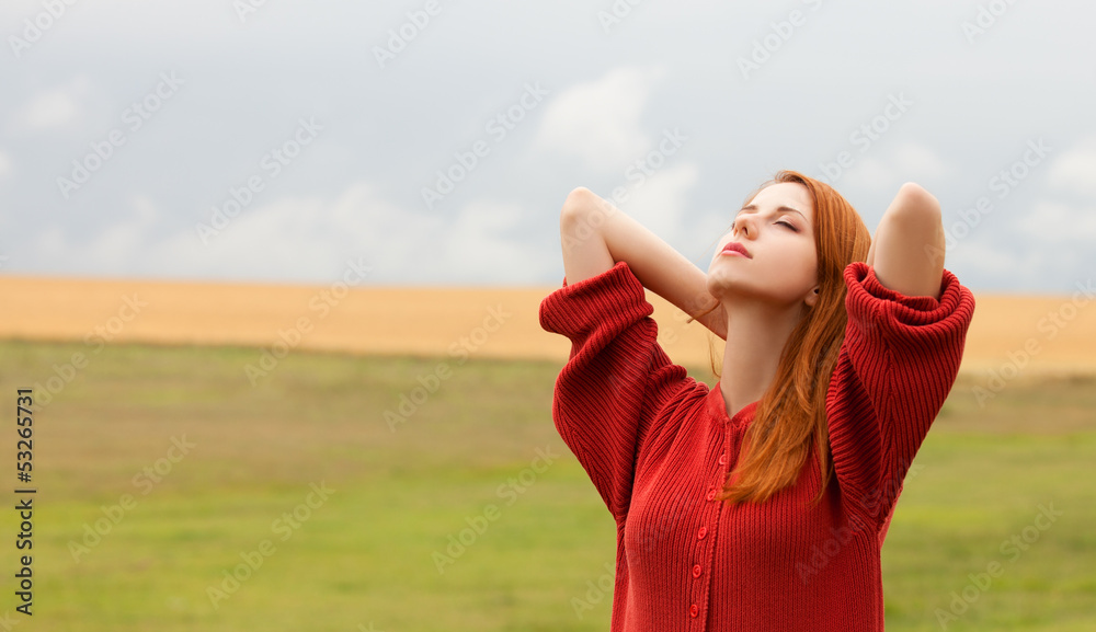 Redhead girl at meadow near wheat field