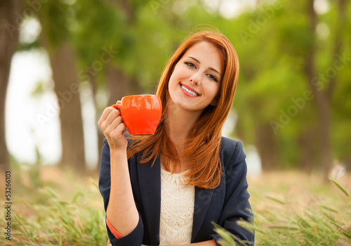 Redhead girl with orange cup at outdoor