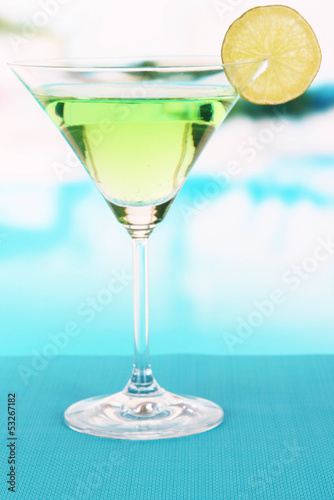 Green cocktail with lime on table on bright background
