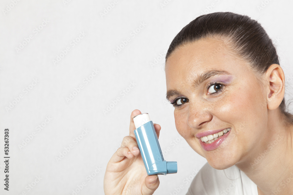 Cute smiling girl using an asthma inhaler for preventing attacks Cute smiling girl using an asthma inhaler for preventing attacks
