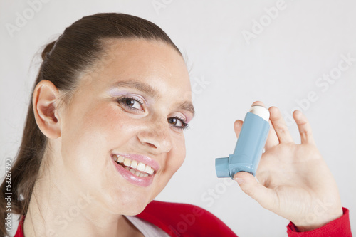 Cute smiling girl showing-using an asthma inhaler