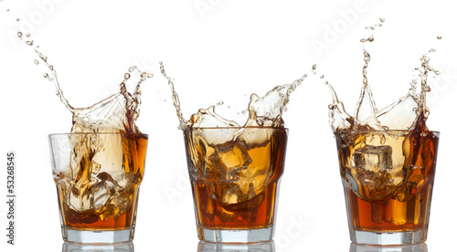 whiskey set splashing out of glass on white