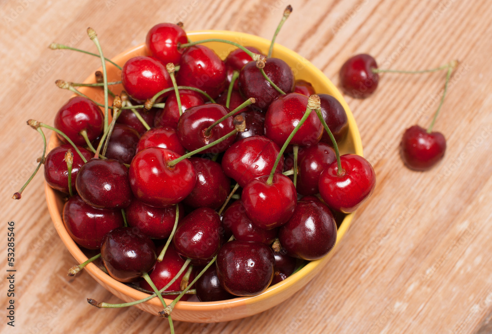 ripe cherries in a yellow bowl, top view ripe cherries in a yellow bowl, top view