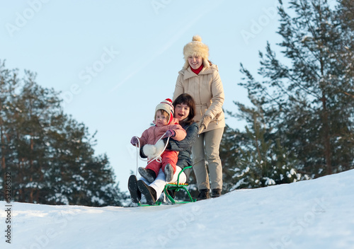 Two women with child sliding on sleds