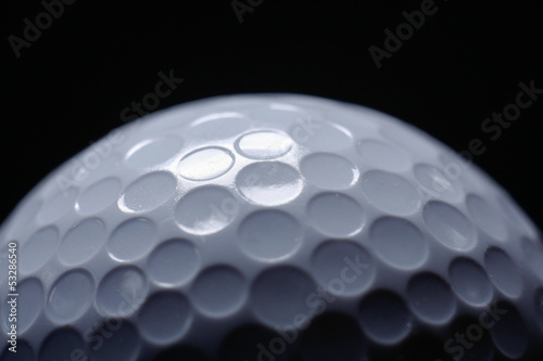 A close-up of a golf ball over dark background