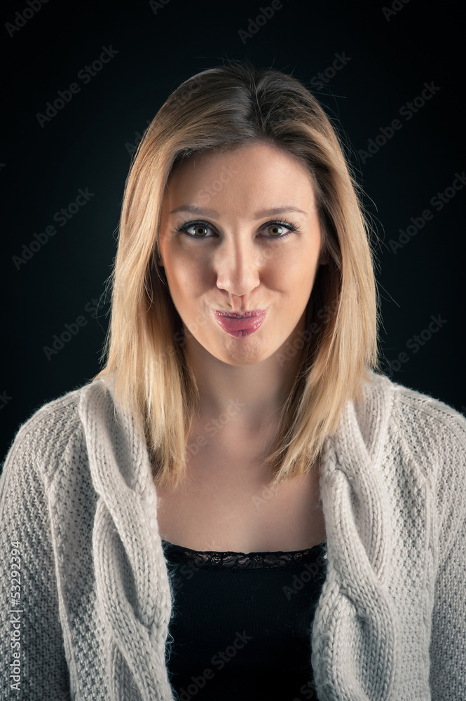 Blonde woman close up portrait on dark background. Tongue out. Blonde woman close up portrait on dark background. Tongue out.