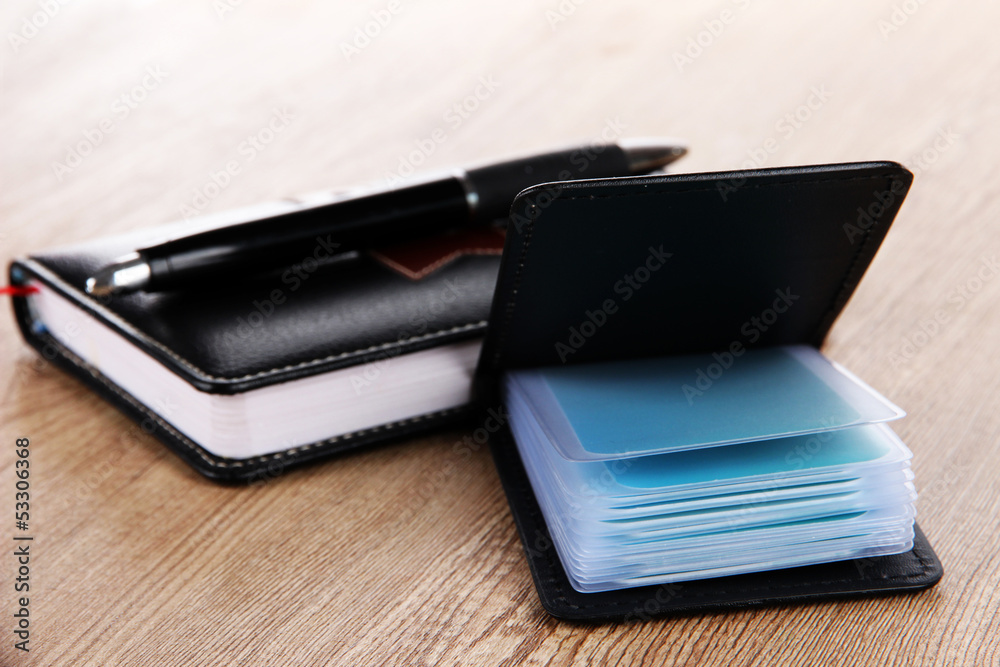Black business card holder notebook and pen on wooden Black business card holder notebook and pen on wooden