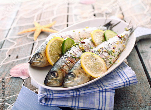 Foto Three grilled sardines on a platter outdoors