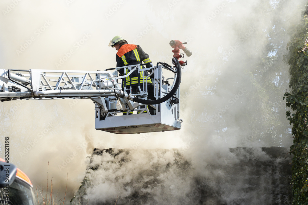 Fototapeta premium Drehleiter der Feuerwehr vor brennendem Haus