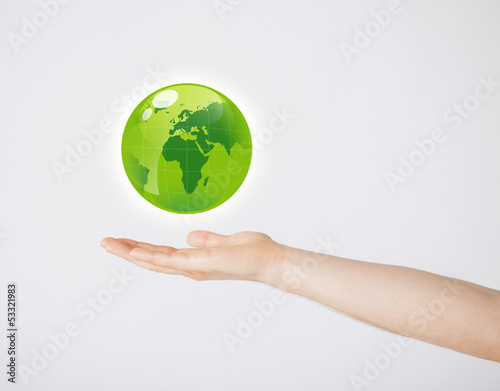 mans hand holding green globe