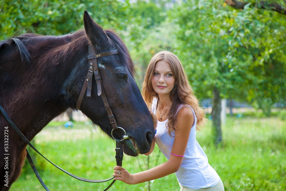 Obraz premium Young girl walking with a horse in the garden.