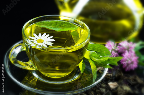 Cup with green tea and green leaves.