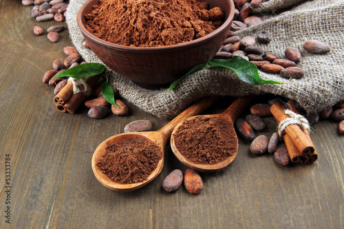 Cocoa powder and cocoa beans on wooden background