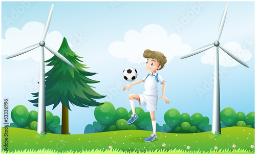 A boy playing football near the windmills