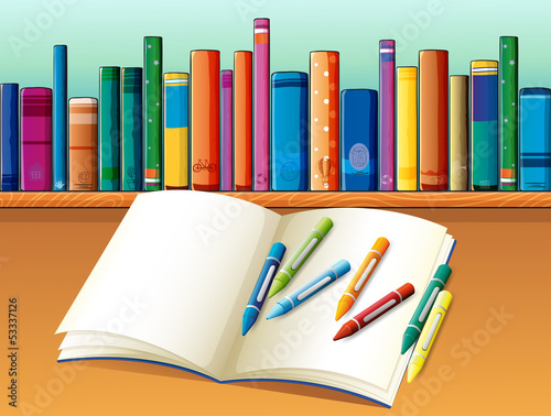An empty notebook with crayons in front of the shelf with books