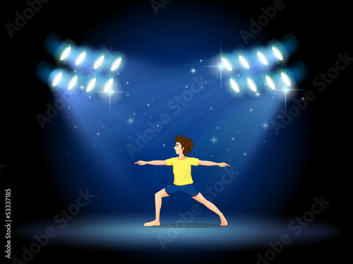 A boy exercising at the stage with spotlights