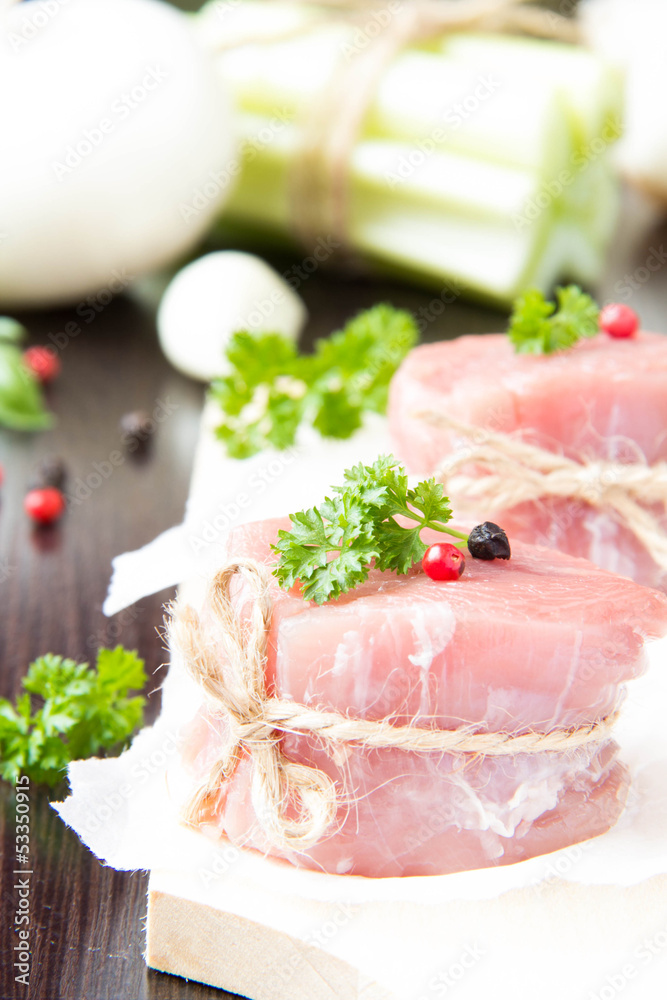 Fresh fillet of raw meat with spices and herbs on a wooden backg Fresh fillet of raw meat with spices and herbs on a wooden backg