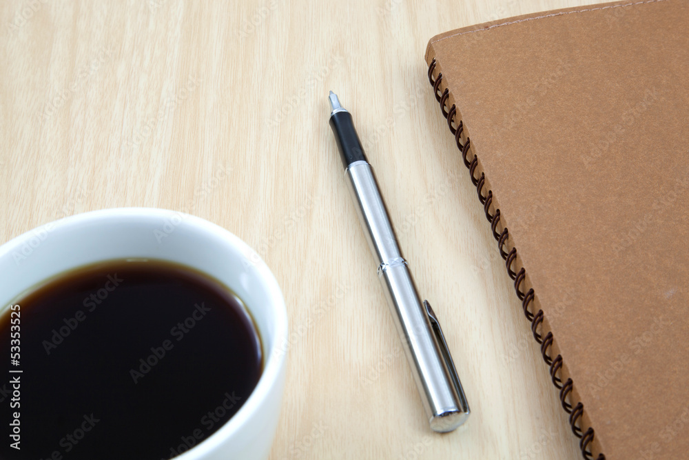 Cup of coffee on a wooden table with book and pen Cup of coffee on a wooden table with book and pen