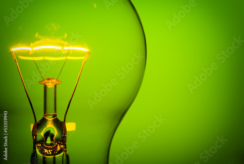 Valokuvatapetti Close up glowing light bulb on green background