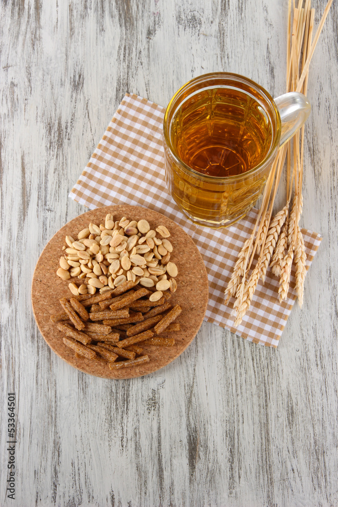 Beer in glass crunches, and nuts on napkin on wooden table