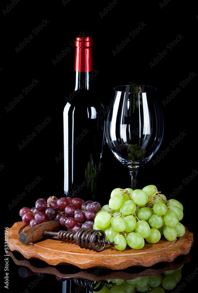 Bottle of red wine with glass and grapes on wooden board