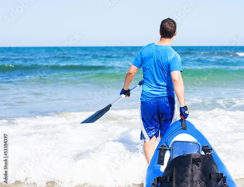 young man carrying his kayak into the water